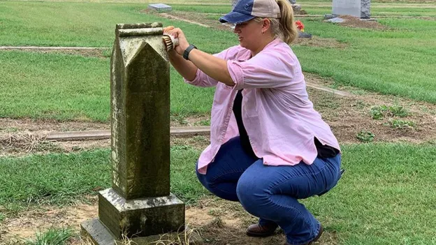 Woman cleaning a headstone in a cemetary