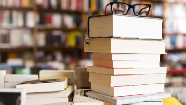 glasses on top of stack of art books lying on table in bookstore