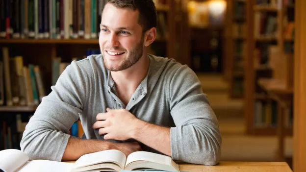 Smiling male student working in a library