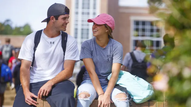 Two students having a conversation outside while others walk past
