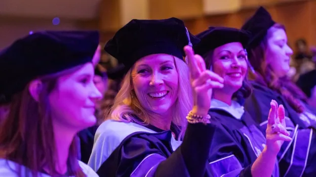 Students at the graduate ceremony with axes up