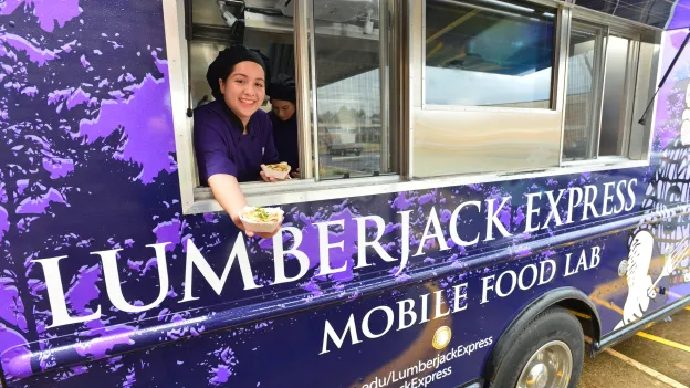 Student offering food from mobile food lab