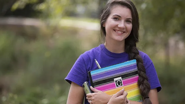 Student holding her folder and smiling at the camera