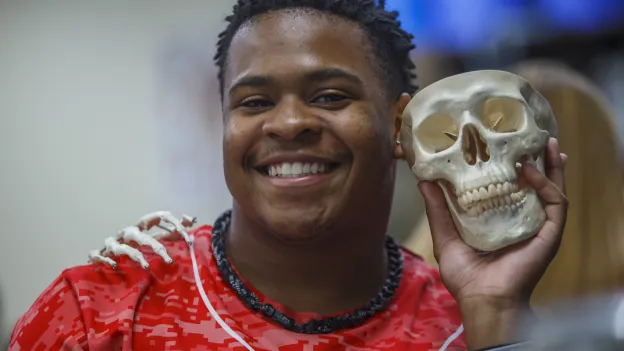 Student smiling at the camera and posing with a skeleton