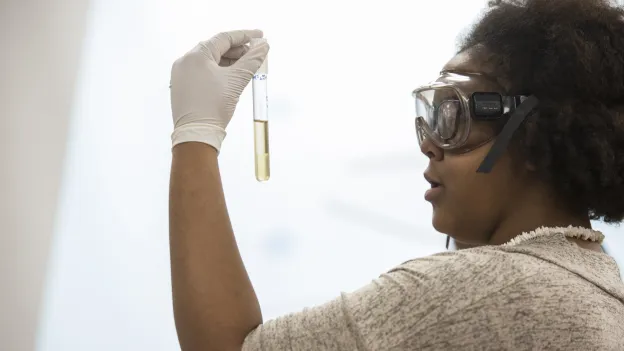 Student wearing safety goggles and inspecting a sample