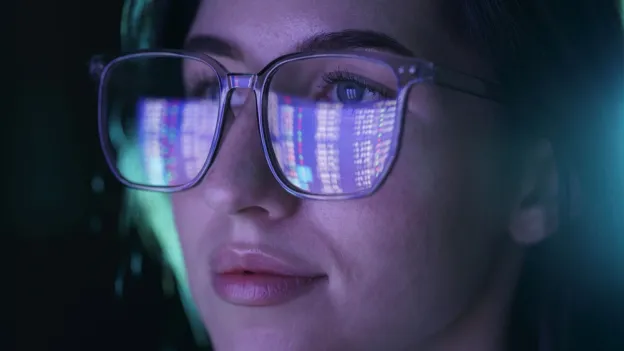 Woman wearing glasses while looking at computer code