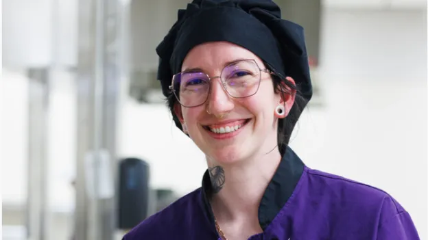 Student smiling while participating in a food demo lab