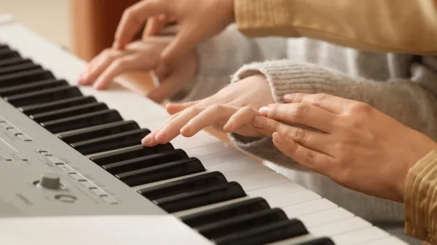 Closeup of instructor guiding a student's hands to proper piano placement