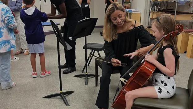 Child learning proper hand placement for cello