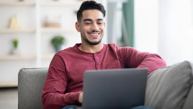 Man sitting on couch looking at laptop