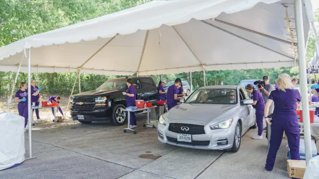 SFA School of Nursing students provide flu shots to car passengers underneath a large canopy