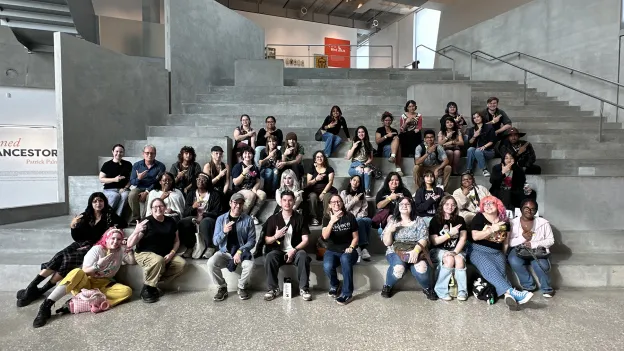 Over three dozen SFA art students and faculty members line a broad concrete stairway, giving the SFA axe 'em hand sign