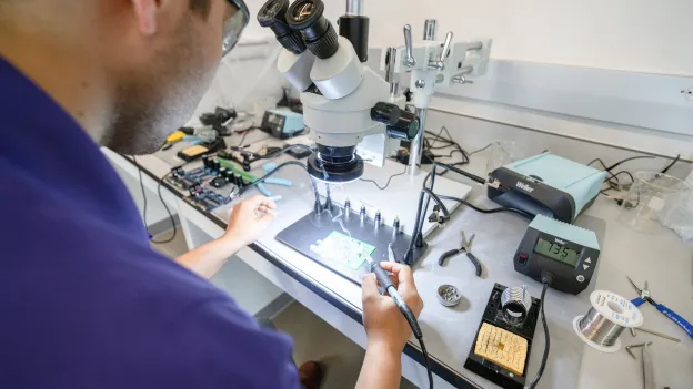 An SFA student solders components onto a circuit board