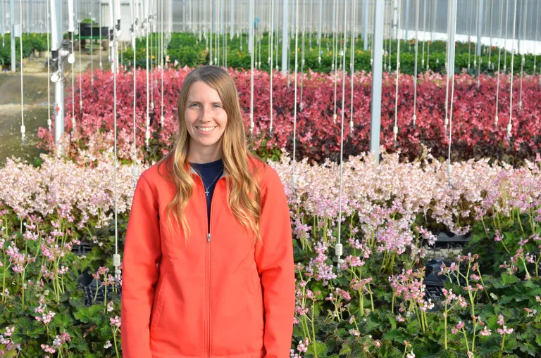 Brooke McGown stands against a backdrop of flowers in a nursery