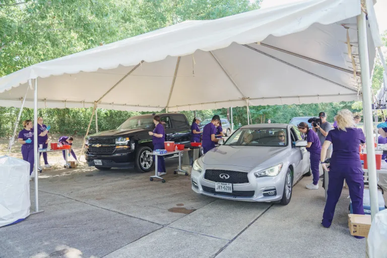 SFA School of Nursing students provide flu shots to car passengers underneath a large canopy