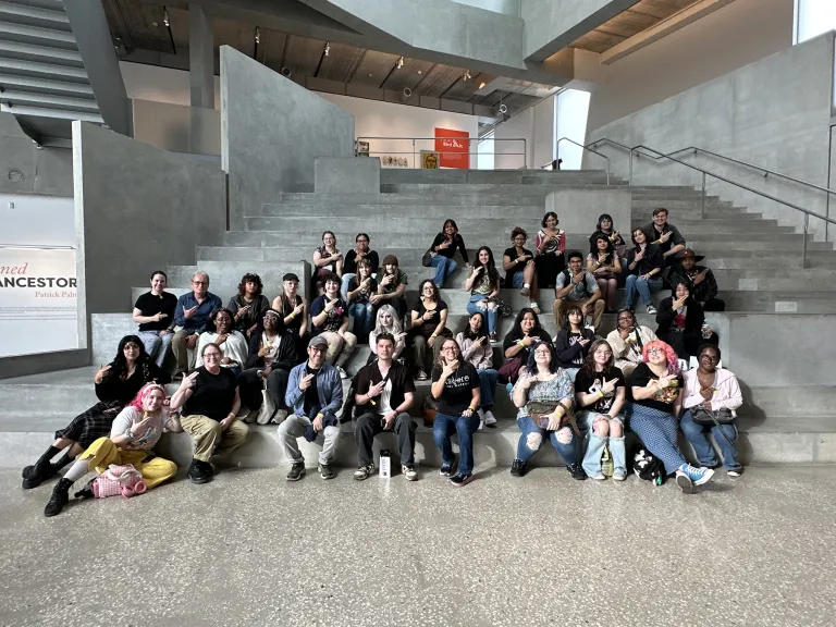 Over three dozen SFA art students and faculty members line a broad concrete stairway, giving the SFA axe 'em hand sign