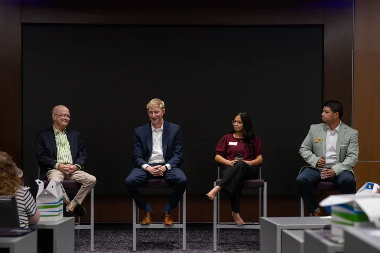 Four panel members sitting on stools discuss topics in banking