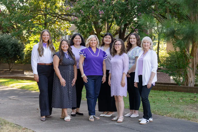 Cole Student Success Center staff members stand together outdoors with trees and other greenery in the background
