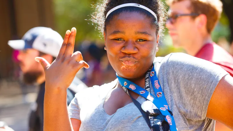 Student does kissy face and shows axe em hand sign
