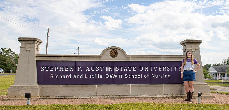 Lacie Shepherd standing outside DeWitt School of Nursing sign