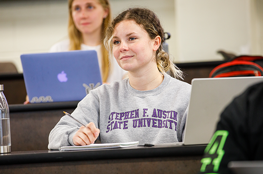 female student in class with laptop