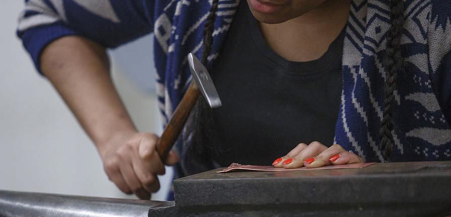 A student works with metals on an anvil