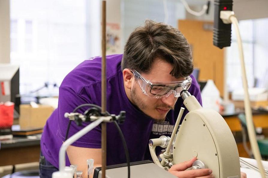 Student wearing safety goggles working with a laboratory instrument