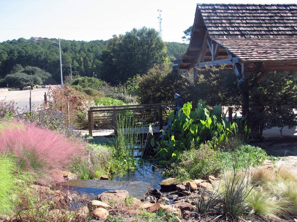 A timber frame pavilion is shown among a variety of grasses and blooms