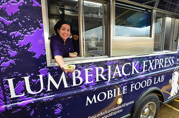 Student offering food outside the window of the food truck