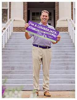 Dr. Neal Weaver holding I'm a Lumberjack banner
