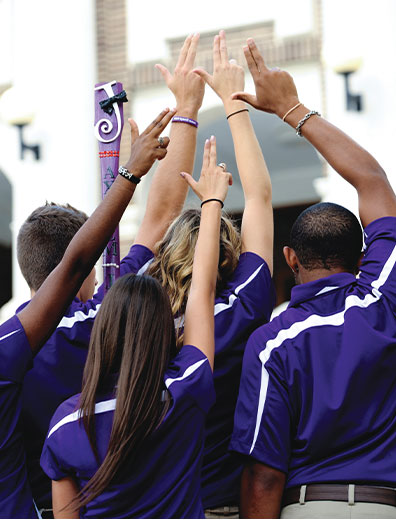 Students with their backs to the camera holding up the Axe 'Em, Jacks hand sign
