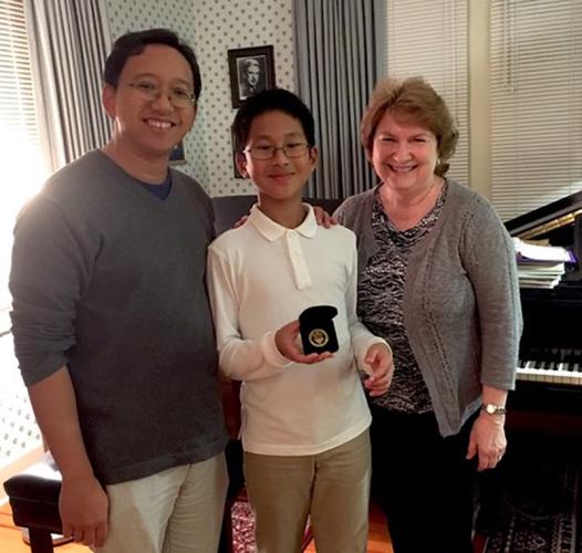 Nio Ajero showcases an award alongside Mario Ajero and his teacher Linda Parr.