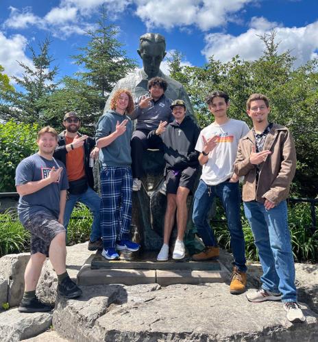 The SFA Baja SAE team with a statue of Nikola Tesla