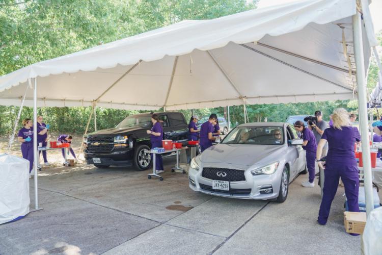 SFA School of Nursing students provide flu shots to car passengers underneath a large canopy
