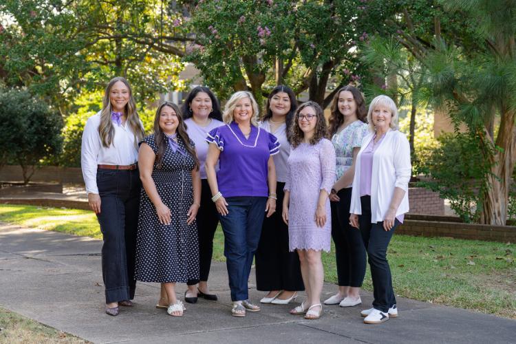 Cole Student Success Center staff members stand together outdoors with trees and other greenery in the background