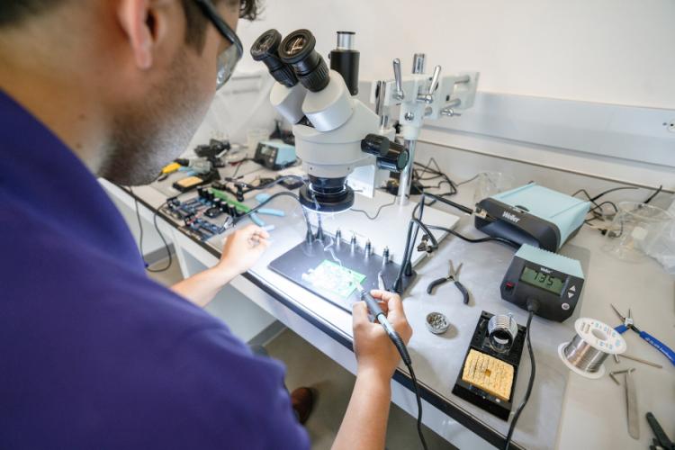 An SFA student solders components onto a circuit board