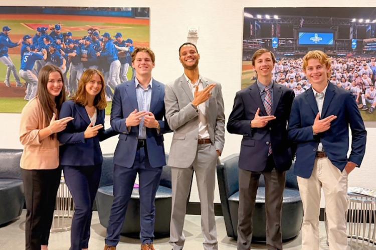 Members of SFA's Sports Business Society dressed in business casual attire give the Axe 'Em hand sign 